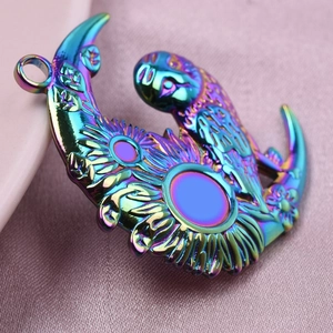 Macro shot of 18k plated parrot on crescent moon pendant with iridescent rainbow finish