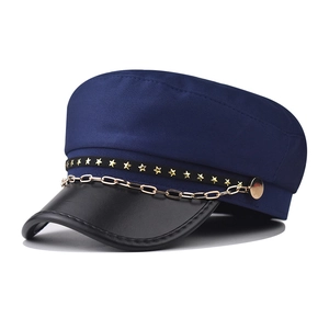 Close-up of military cap featuring gold metal chain and star rivets on leather brim