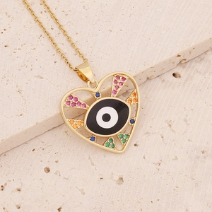 Macro shot of gold heart necklace with colorful zircon evil eye pendant on stone