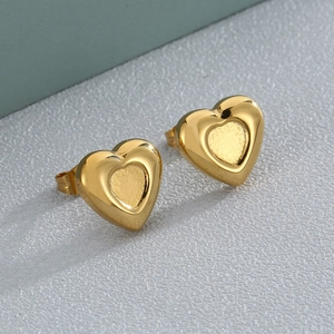 Chic gold heart stud earrings with polished edges and matte center on grey surface