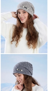 Detail of grey winter knit beanie featuring cable pattern and small brand label on the side