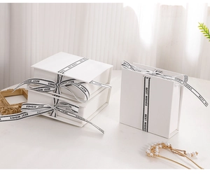 Detailed view of white flip-top jewelry gift boxes with branded Best Wishes ribbon
