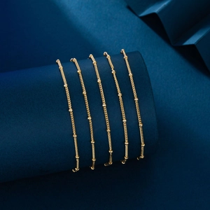 Detailed view of five gold beaded bracelets displayed on a navy blue jewelry stand