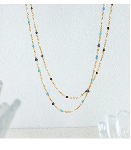 Detail showing the gold chain necklace with colorful deep blue and turquoise beads