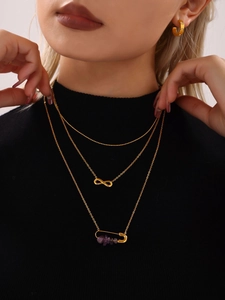 Collier doré à trois rangs avec symbole infini et pendentif épingle à nourrice et pierres