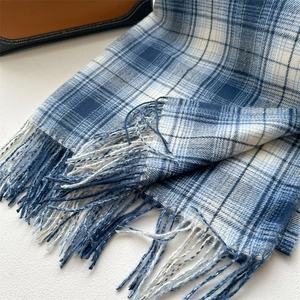 Close-up detail of soft blue and white plaid scarf fabric with elegant tassel fringe