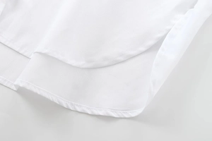 Gros plan détaillé d'une chemise en coton blanc montrant l'ourlet arrondi et les coutures