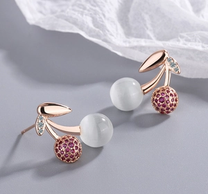Macro detail of cherry stud earrings in rose gold with opal beads and pink zircons