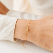 Detail of 18K gold chain bracelet with crystal letter A pendant on woman wrist