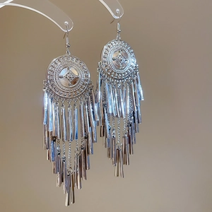 Detailed macro view of silver circular embossed earrings with long metal tassels
