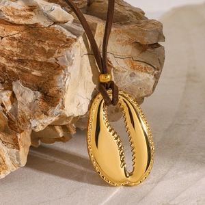 Close-up of shell pendant with gold texture on brown leather cord over natural stones