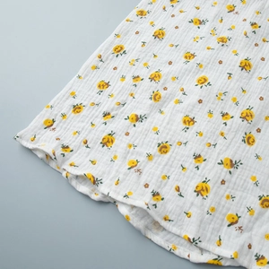 Gros plan sur le tissu en coton crépon blanc avec imprimés floraux jaunes et texture douce