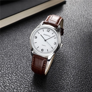 Macro shot of silver quartz watch dial with Arabic numerals and brown leather strap