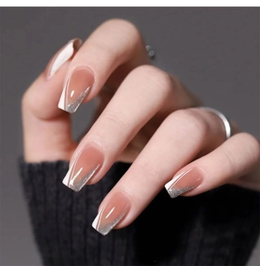 Close-up of coffin press-on nails with nude base, white French tips and silver glitter detail
