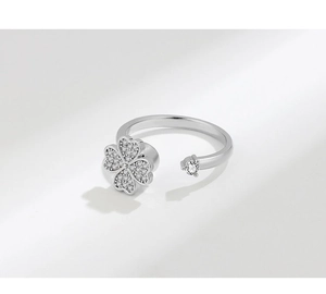 Detailed view of silver rotatable clover ring with sparkling zircons on white backdrop