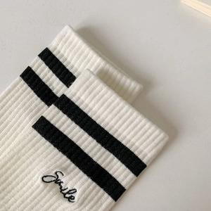 Macro detail of Smile embroidery and double black stripes on white ribbed athletic socks