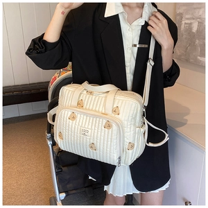 Détail du sac à langer matelassé beige à motif ours suspendu à une poussette