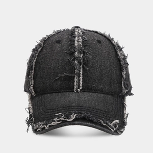 Gros plan d'une casquette en denim noir vieilli avec bords effilochés et coutures rétro