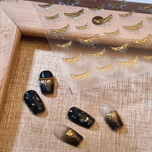 Golden liquid tassel nail stickers with 3D metallic texture on elegant warm background