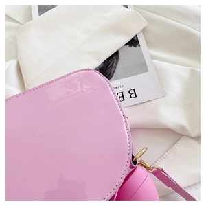Detailed close-up of the pink patent leather crossbody bag with precise stitching