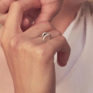 Gros plan d'une bague ouverte argentée irrégulière sertie de diamants portée au doigt