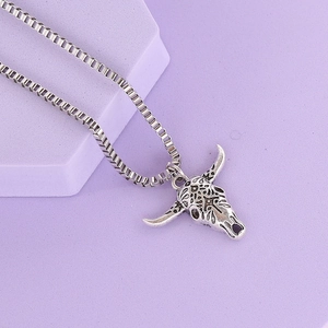 Silver bull head pendant necklace with tribal carvings on purple display stand