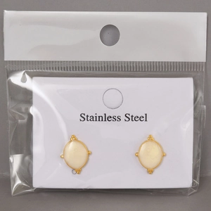 Detail view of gold-plated stainless steel earrings with cream oval enamel in packaging