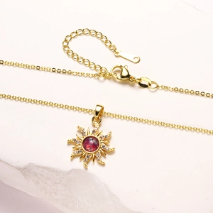 Vista detallada del collar con colgante de sol bañado en oro 18K y circón rojo