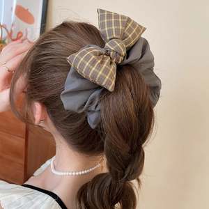 Detail view of a large plaid bow scrunchie on a ponytail with retro fabric texture