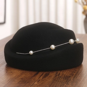 Détail du béret en laine avec perles blanches élégantes et chaîne en strass scintillante