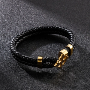 Detail of gold metal buckle with cutout logo on black braided leather double bracelet