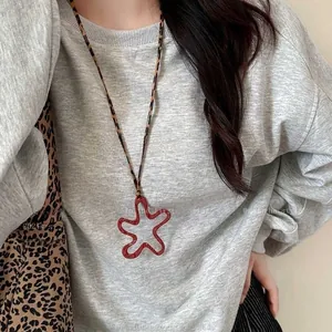 Close-up of a red star pendant with a leopard print cord on a casual grey sweatshirt