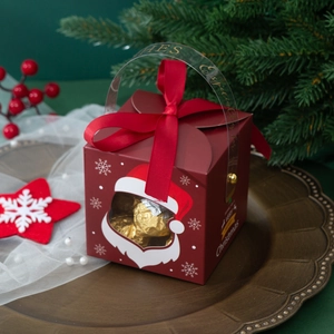 Red Christmas hollow-out gift box with Santa window and gold ribbon on a vintage plate