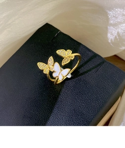 Macro view of gold plated adjustable ring with three cubic zirconia butterfly charms