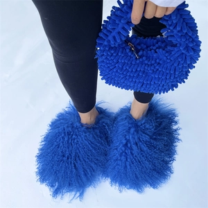 Detail of plush Klein blue handbag and matching furry slippers set on snowy ground