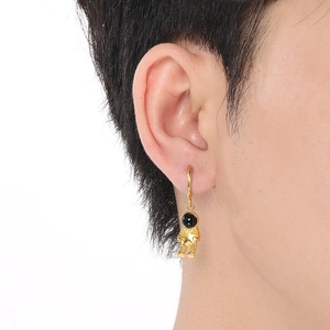 Detail of a gold astronaut earring with black helmet and star decoration on the ear