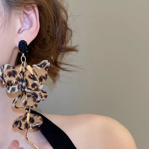 Detail of leopard print fabric flower earrings with black gemstone and golden wave tassel