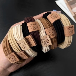 Elastische Haargummis mit Bärenanhänger in neutralen Tönen wie Schwarz, Kaffee und Creme
