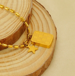 Dettaglio collana in titanio dorato con piastra a scacchi e ciondolo a stella