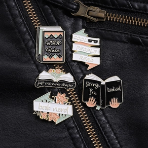 Close-up of colorful enamel book pins featuring slogans on a black leather jacket texture