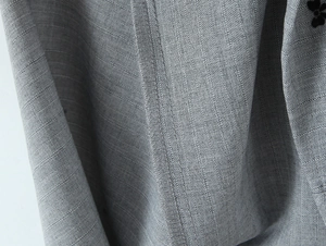 Macro shot of grey herringbone knit fabric with a 3D black floral applique detail