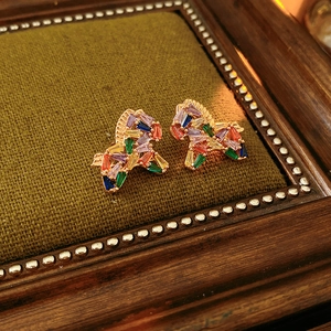 Macro shot of colorful zircon horse stud earrings on a green velvet vintage jewelry tray