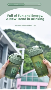 Close-up of a green translucent protein shaker bottle with a handle held in hands outdoors