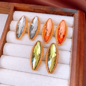 Macro detail of marquise-cut crystal earrings in grey, orange, and yellow-green colors