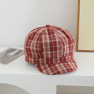 Dettaglio del berretto newsboy in tweed a quadri rosso e beige per bambine alla moda