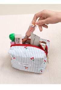 Detail einer Hand, die Kosmetik aus der gesteppten Kirsch-Kulturtasche mit Reißverschluss nimmt