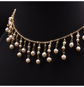 Detailed macro view of cascading freshwater pearl tassels on a golden metal chain necklace