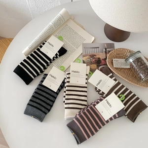 Close-up of five pairs of striped cotton crew socks in retro earthy tones on white table