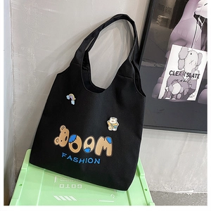 Detail der schwarzen Canvas-Tasche mit Boom Fashion-Aufdruck und niedlichen Bären-Aufnähern