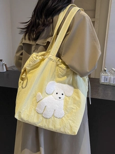 Large pale yellow canvas tote bag with cute plush puppy patch shown on model shoulder